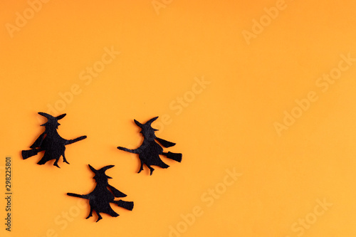 Three black witches on orange background. Minimal flat lay. Halloween © troyanphoto