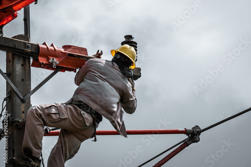 The lineman are replacing damaged insulator insulators by using insulated wire-tong sets, tie stick and robe box sets in sliding wires going out in a safety working distance.