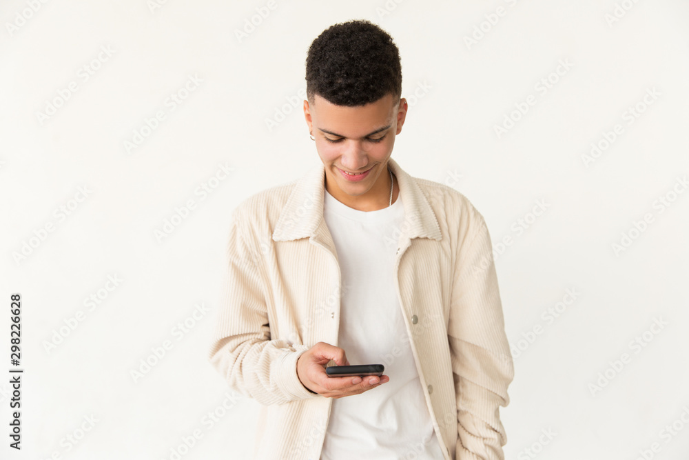 Smiling young man using smartphone. Portrait of handsome happy young man standing and using mobile phone. Technology concept Smiling young man using smartphone. Portrait of handsome happy young man standing and using mobile phone. Technology concept