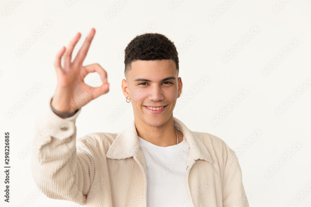 Happy young man showing ok sign. Portrait of handsome happy young man showing ok symbol with hand and smiling at camera. Gesture concept Happy young man showing ok sign. Portrait of handsome happy young man showing ok symbol with hand and smiling at camera. Gesture concept