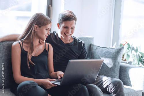 close up. young family with laptop sitting on sofa in living room.