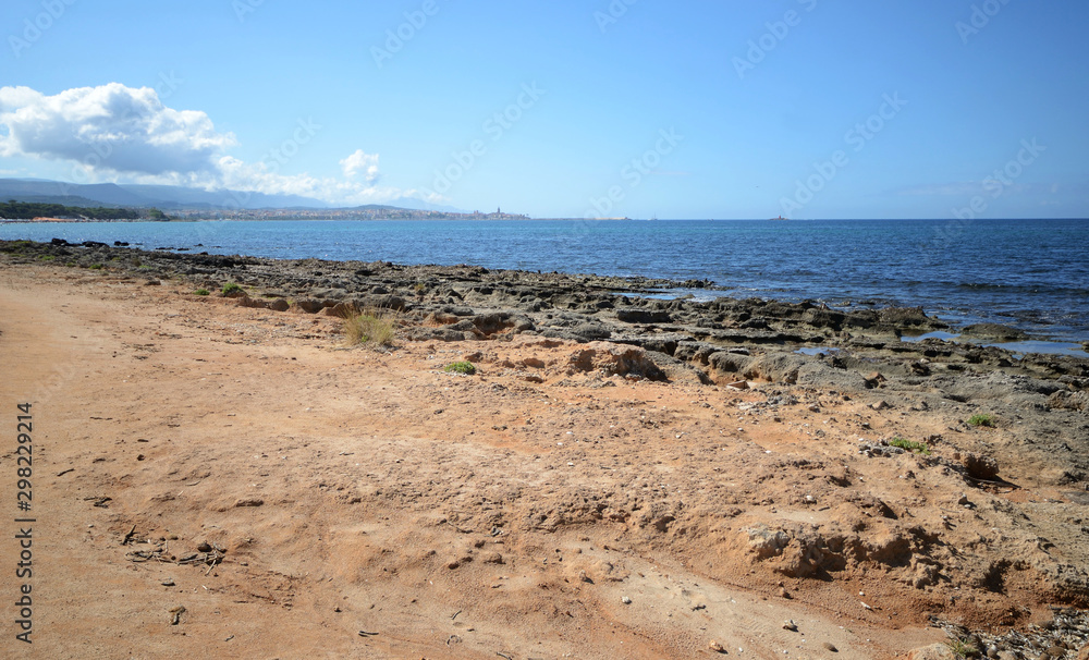 Pink Rocky beach and Mediterranean sea in Sardinia Island. Alghero town in the background Pink Rocky beach and Mediterranean sea in Sardinia Island. Alghero town in the background