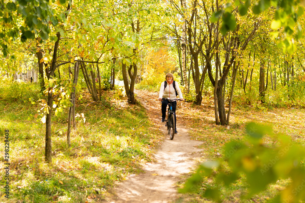 A woman on a Bicycle rides through the autumn Park among the trees.