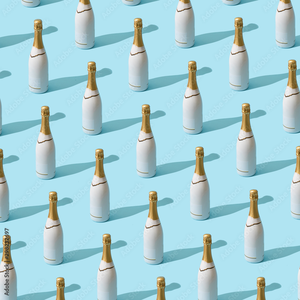 Trendy Christmas pattern made with white champagne bottle on bright light blue background. Minimal Christmas party concept. - obrazy, fototapety, plakaty 