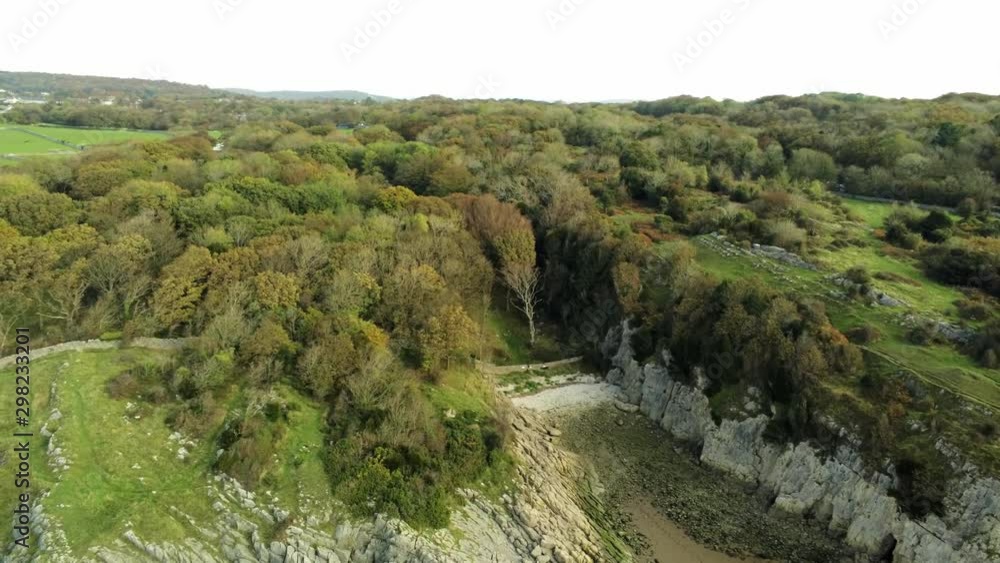 Aerial view across coastal cliff edge rocky boulder stone formation & sandy beach tide out. Lake district. Wide aerial pull back orbit right above idyllic countryside. Aerial view across coastal cliff edge rocky boulder stone formation & sandy beach tide out. Lake district. Wide aerial pull back orbit right above idyllic countryside.
