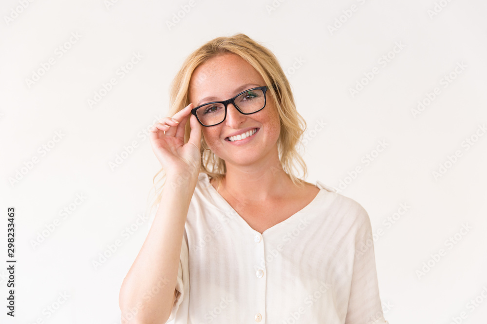 Happy joyful young woman adjusting her glasses. Beautiful woman in casual posing isolated over white background, touching eyewear. Vision concept