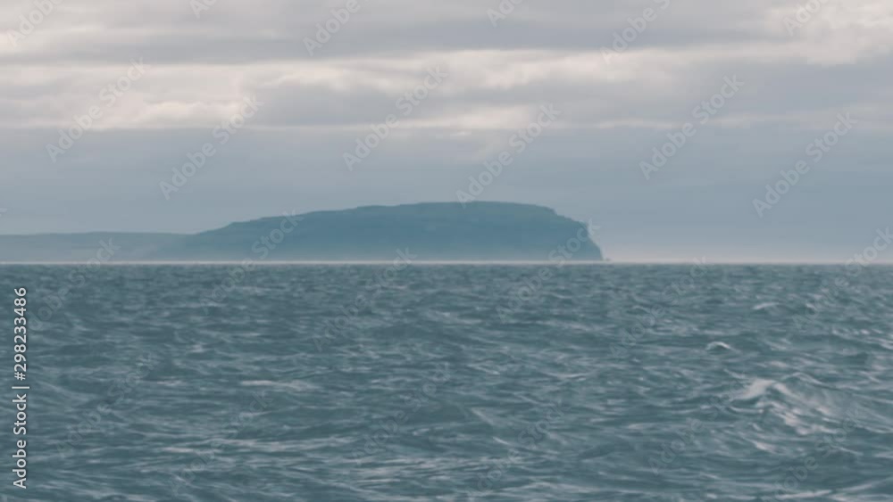 Distant island and cliff, epic serene slow motion, with hazy horizon Distant island and cliff, epic serene slow motion, with hazy horizon
