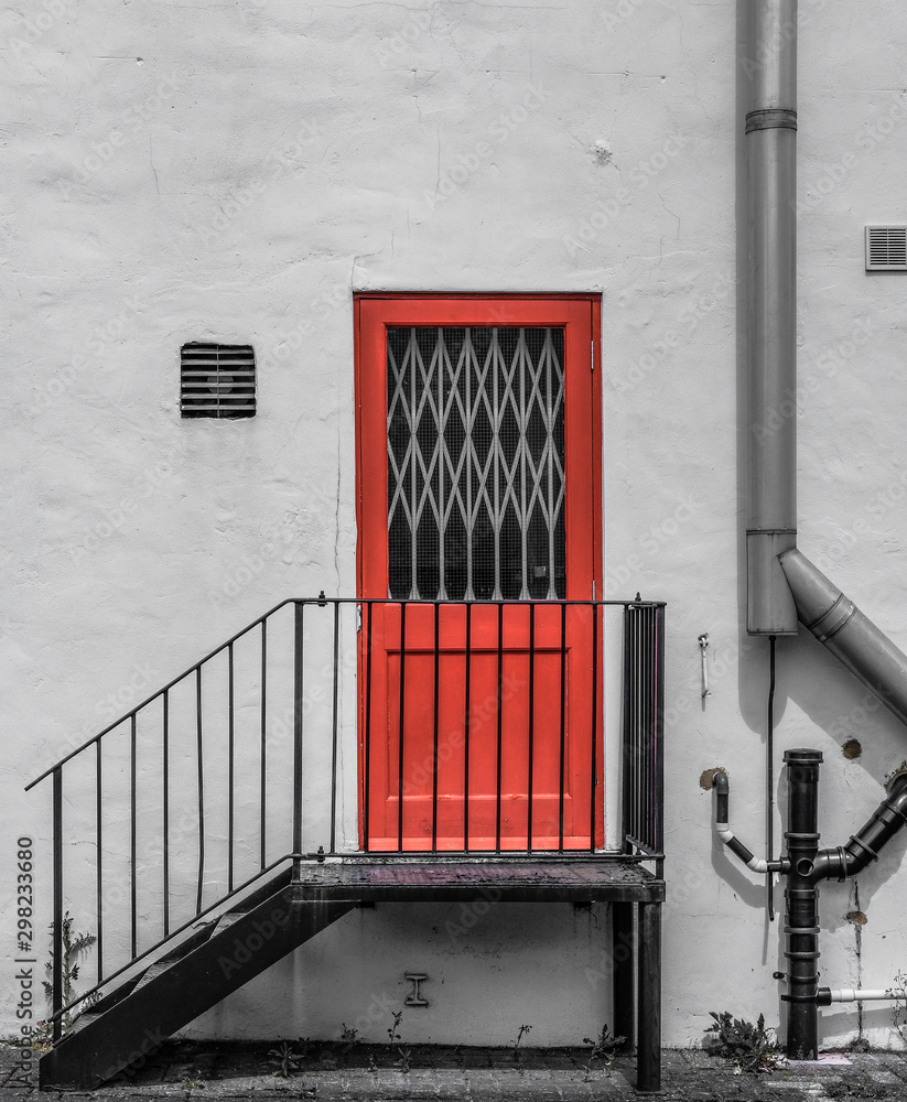 Obraz premium Locked fire door seen at the side of a factory entrance with newly installed pipe work visible.