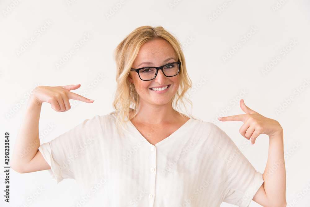 Joyful young woman in glasses pointing fingers at herself. Beautiful woman in casual posing isolated over white background. Advertising concept Joyful young woman in glasses pointing fingers at herself. Beautiful woman in casual posing isolated over white background. Advertising concept