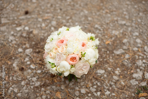 Wedding bouquet lying on grey carpet during preparation before celebration. Side view of decorative rose peonies flowers and leaves bouquet