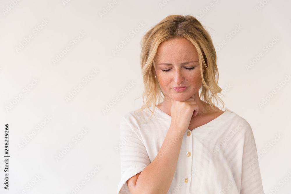 Upset young woman suffering from sore throat. Beautiful woman in casual posing isolated over white background, touching throat with closed eyes. Catching cold concept Upset young woman suffering from sore throat. Beautiful woman in casual posing isolated over white background, touching throat with closed eyes. Catching cold concept