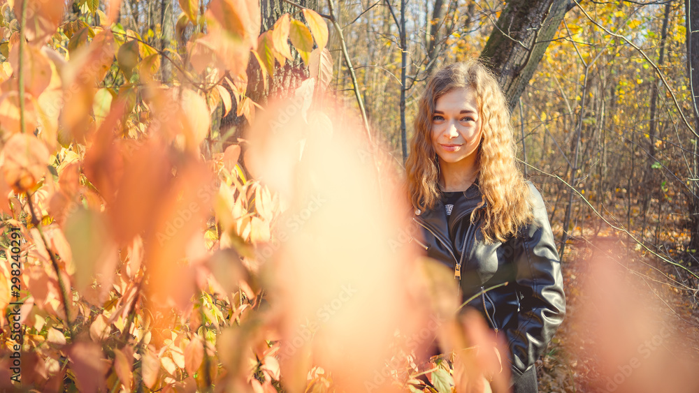 Beautiful woman looking out from behind tree. Pretty calm woman touching tree and looking at camera in quiet forest Beautiful woman looking out from behind tree. Pretty calm woman touching tree and looking at camera in quiet forest