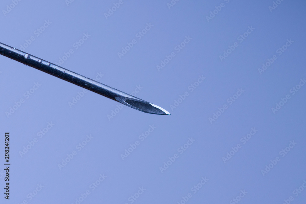 Close-up or macro of syringe needle on a blue background .Hospital, health, care, doctor, injection, vaccine, vaccination, illness, disease, sharpness concepts Close-up or macro of syringe needle on a blue background .Hospital, health, care, doctor, injection, vaccine, vaccination, illness, disease, sharpness concepts
