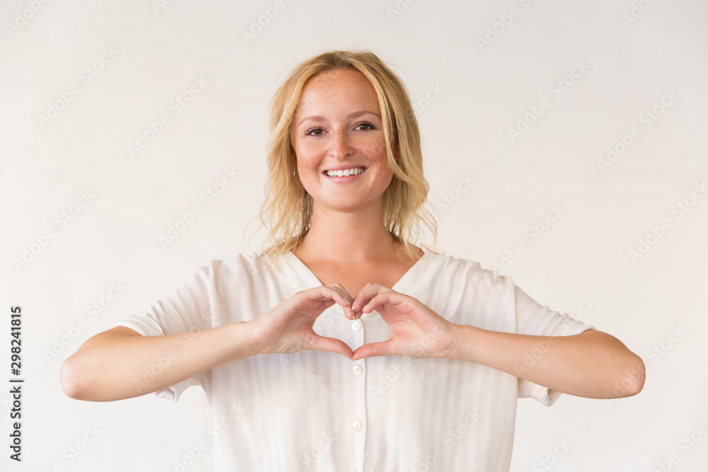 Happy woman showing hand heart gesture. Portrait of beautiful cheerful young woman showing heart symbols with fingers and smiling at camera. Gesture concept Happy woman showing hand heart gesture. Portrait of beautiful cheerful young woman showing heart symbols with fingers and smiling at camera. Gesture concept