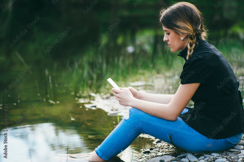 Woman with smartphone on the lake