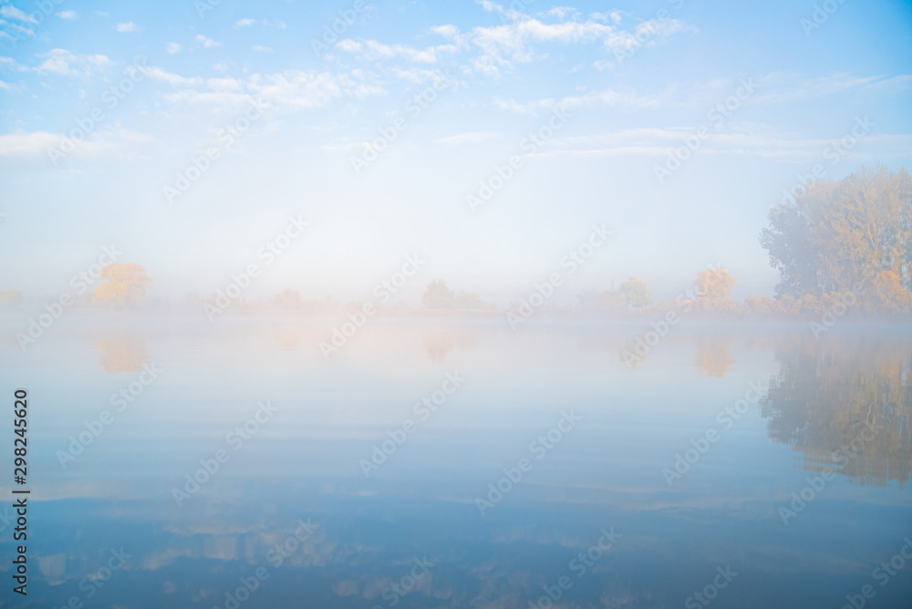 Autumn calm morning on meadow with river. Beautiful sunrise over field with sunlight and mist.