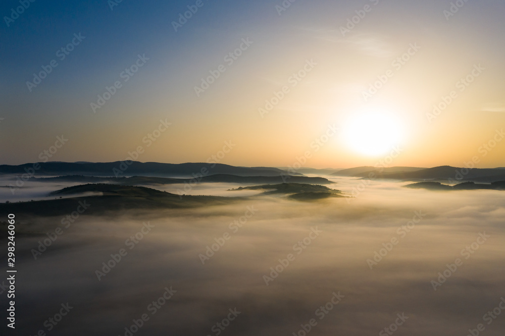 Fototapeta premium Misty sunrise with sunrays over the hills in Transylvania, Romania.