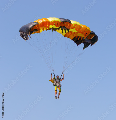 Fotografia Skydiver under canopy of parachute in blue sky