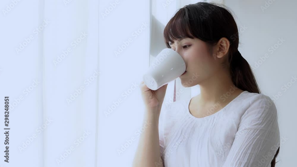 Beautiful portrait young asian woman smile and drink a cup of coffee with relax in the morning at window, girl happy with leisure breakfast is beverage for fresh, lifestyle concept. Beautiful portrait young asian woman smile and drink a cup of coffee with relax in the morning at window, girl happy with leisure breakfast is beverage for fresh, lifestyle concept.
