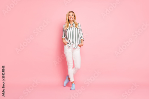 Full length body size photo of cheerful positive cute attractive nice woman holding hands in pockets standing confidently smiling toothily isolated over pink pastel color background