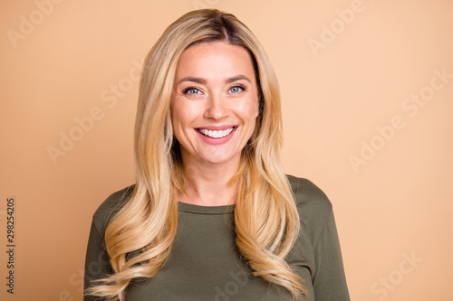 Portrait of cheerful cute nice pretty mature woman looking good smiling in green cheerfully isolated pastel beige color background