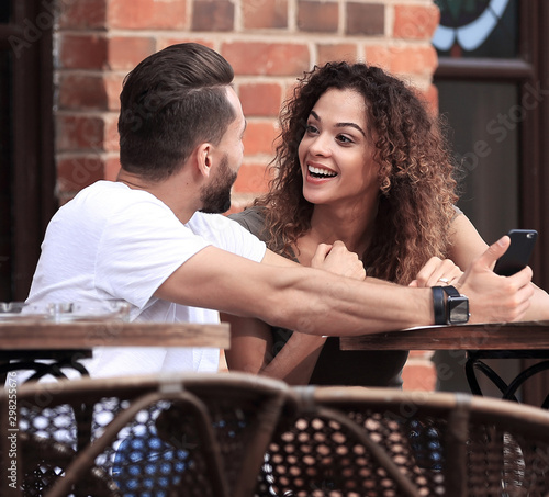 Portrait of a young couple sitting down at a cafe terrace