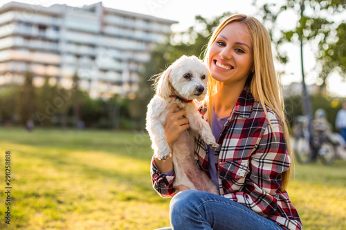 Beautiful woman spending time with her Maltese dog outdoor. 
