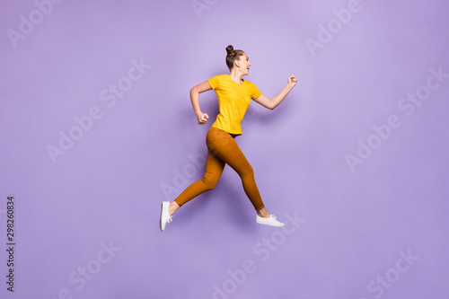 Full length profile photo of amazing lady jumping high rushing to finish line championship race wear yellow t-shirt pants isolated pastel purple background photo