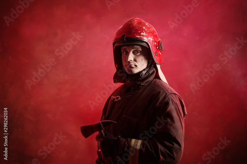 Portrait of firefighter in uniform on dark red background