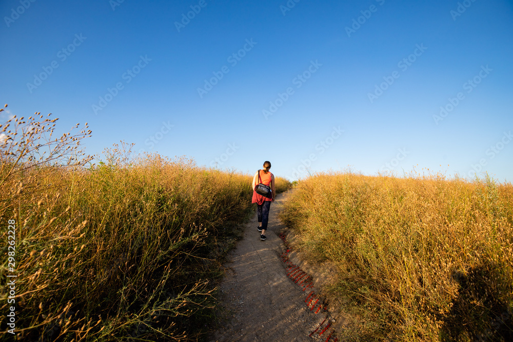 Frau läuft durch dicht bewachsenes Gras auf Feld im Sonnenuntergang