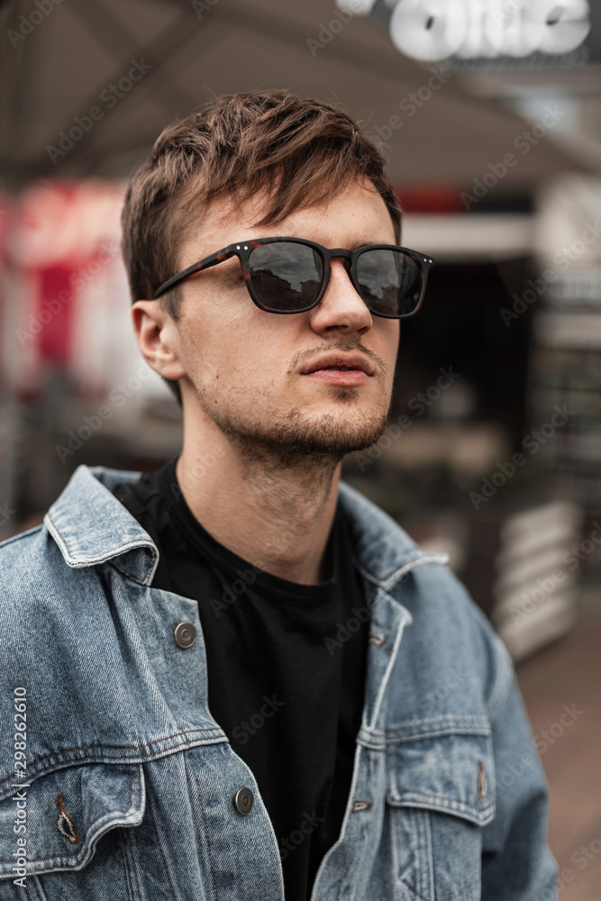 Portrait of a american handsome young man with a beard in fashionable sunglasses in a stylish