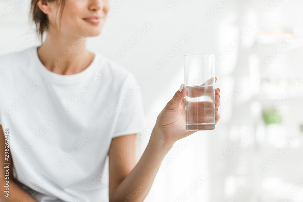 cropped view of smiling girl holding glass of water in the morning cropped view of smiling girl holding glass of water in the morning