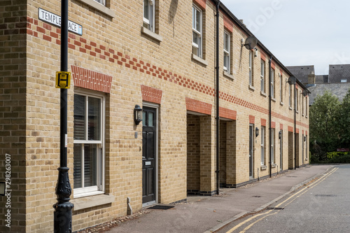 Fototapeta Naklejka Na Ścianę i Meble -  Detailed image of newly build terraced houses seen in a market town in the UK. The road appears to be empty and double yellow lines can be seen.
