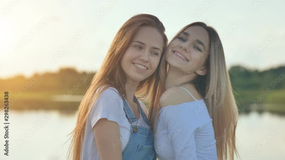 Two girlfriends blondes posing in front of the camera at sunset. Two girlfriends blondes posing in front of the camera at sunset.