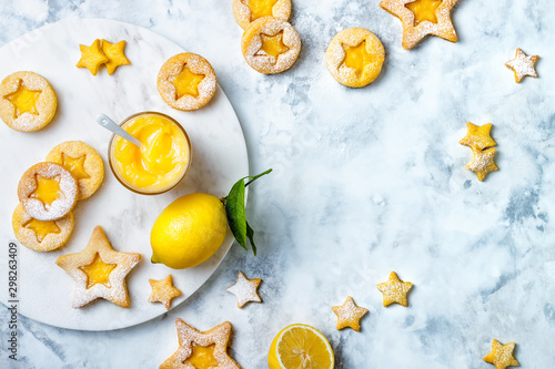 Linzer Christmas cookies filled with lemon curd and dusted with sugar on white marble board photo