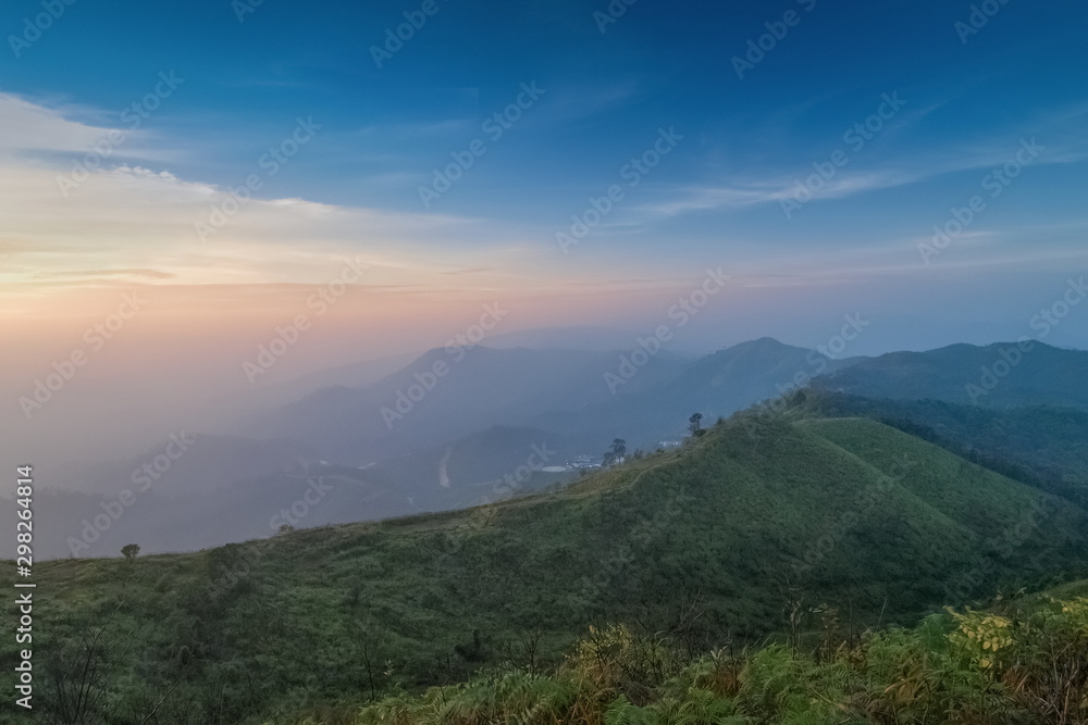 Mountain view evening of top hill around with soft fog with blue sky background, sunset at Nern Chang Suek, Thong Pha Phum, Kanchanaburi, Thailand.