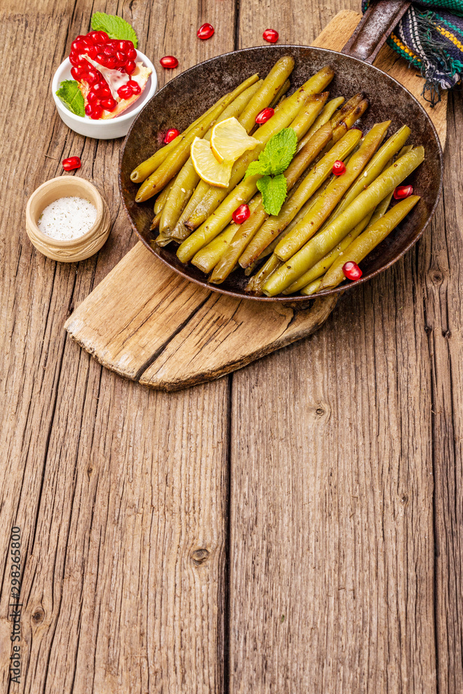 Baked green bean in pan with sesame seeds, pomegranate, mint and lemon Baked green bean in pan with sesame seeds, pomegranate, mint and lemon