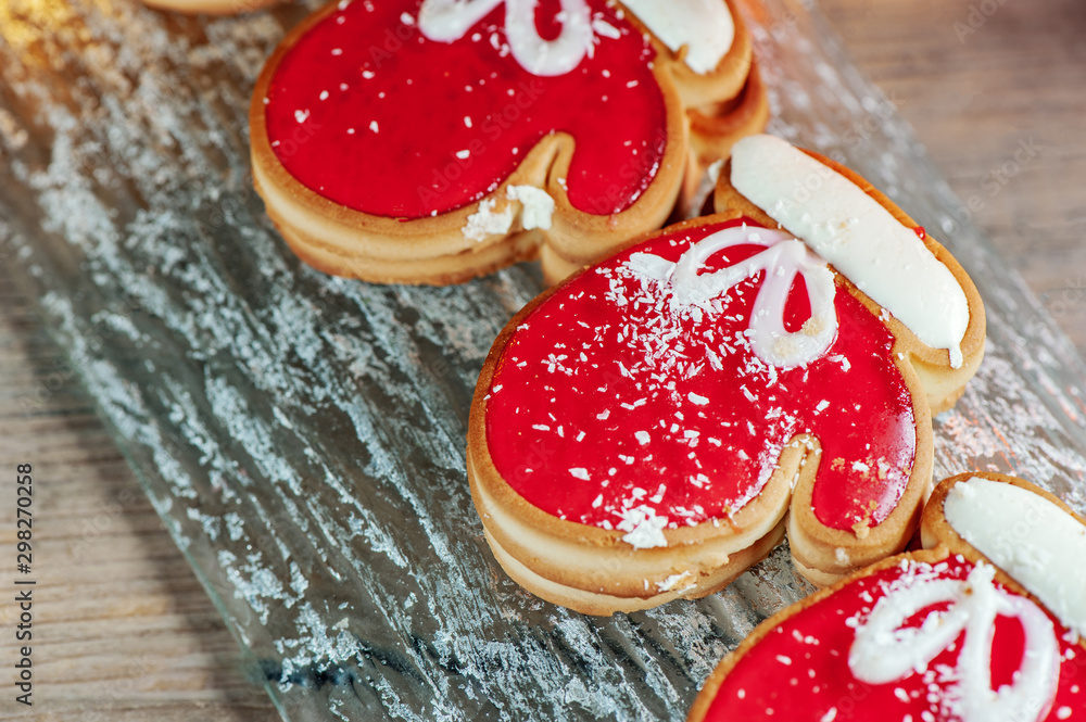 Homemade christmas ginger cookies in the form of red mittens on a glass plate on a wooden table. Christmas card