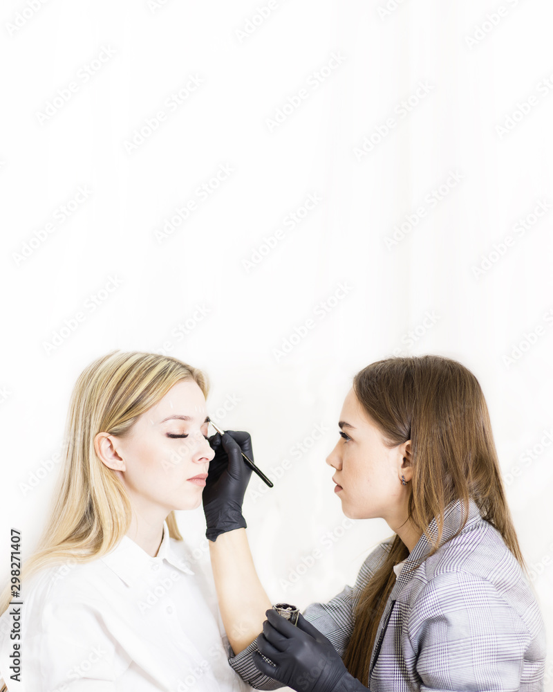 Female cosmetologist performs eyebrow correction on beautiful models in the beauty parlor. The girl's face is a blonde. Close-up. Facial care Female cosmetologist performs eyebrow correction on beautiful models in the beauty parlor. The girl's face is a blonde. Close-up. Facial care