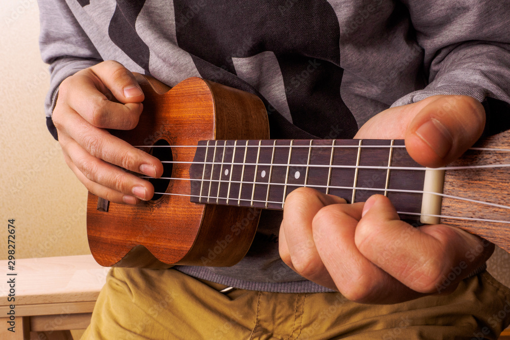 A man playing guitar ukulele in close up view.