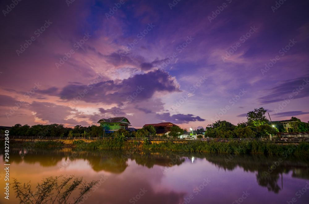 Sunset on twilight with wooden house near river.