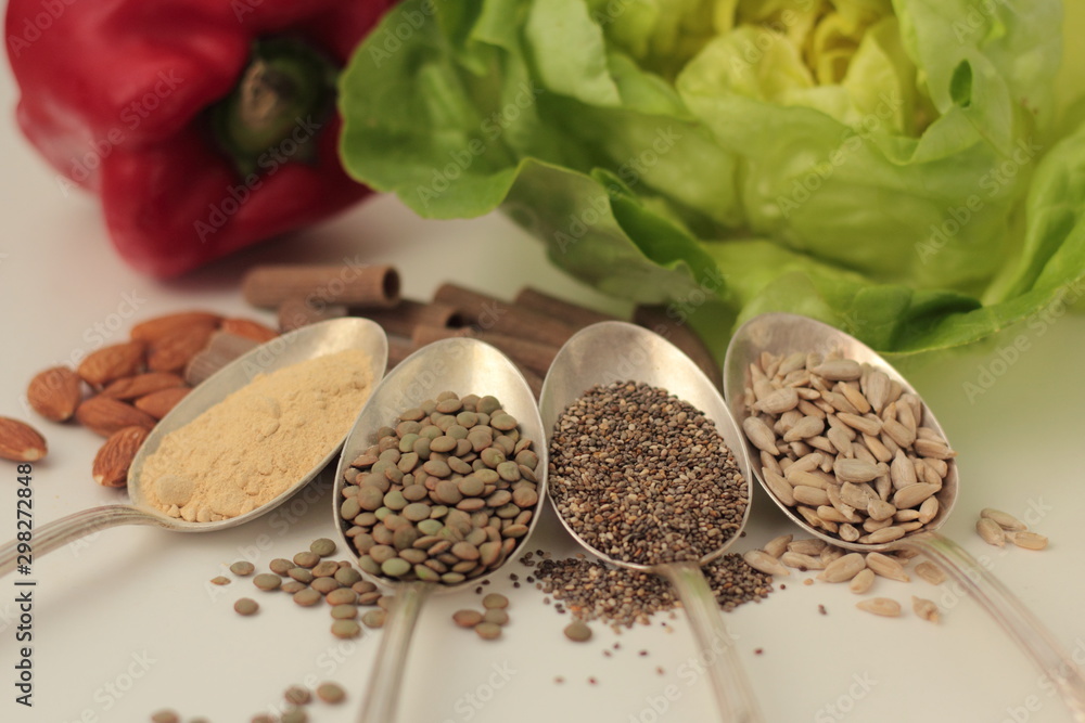 Sample foods from low-GI PCOS (Polycystic Ovary Syndrome) diet. Lentils, maca powder, chia seeds, sunflower seeds, buckwheat pasta, almonds, bell pepper and lettuce.