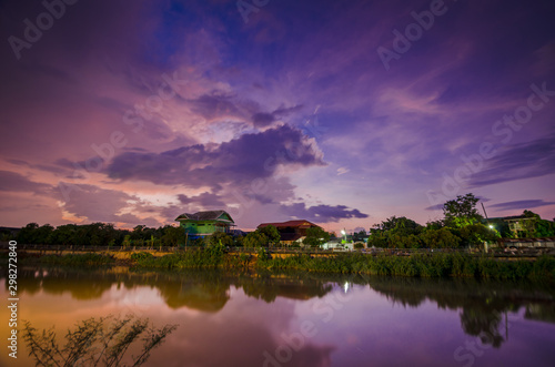 Sunset on twilight with wooden house near river. © gamjai