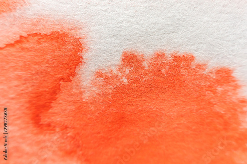 A stain of red watercolor paint on paper. Macro photo. Background minimalistic vibrant image. The concept of drawing.