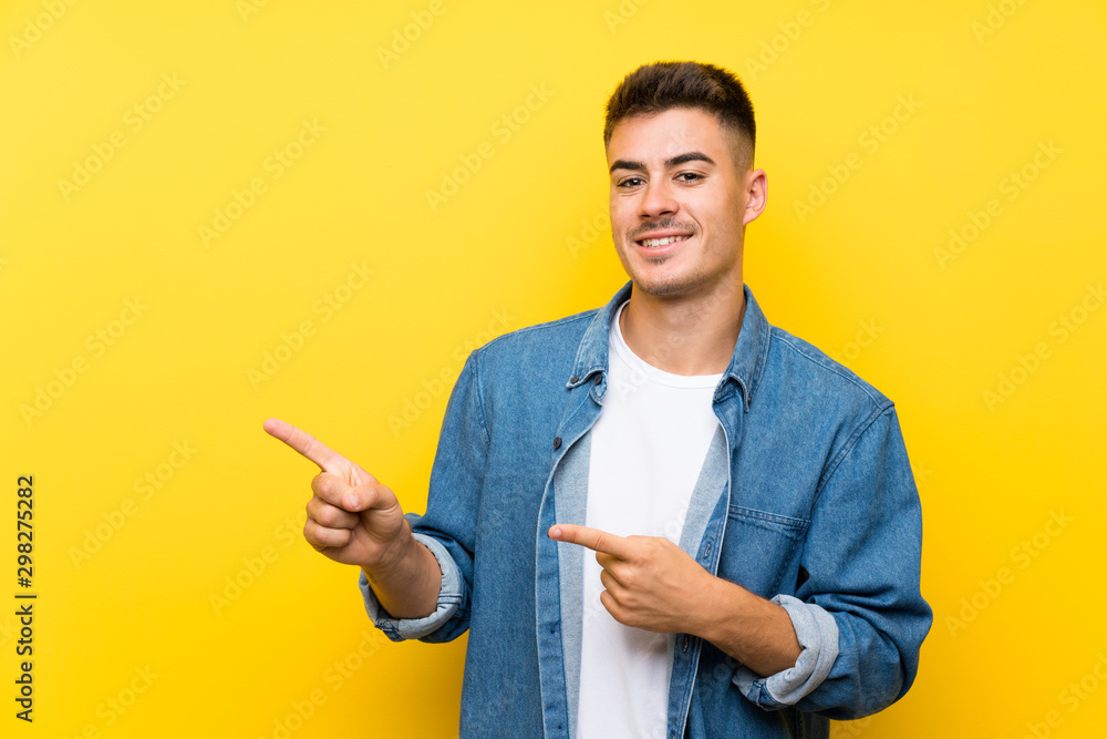 Young handsome man over isolated yellow background pointing finger to the side Young handsome man over isolated yellow background pointing finger to the side
