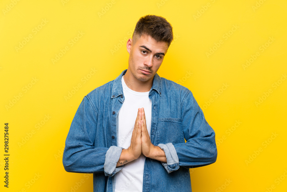 Fototapeta premium Young handsome man over isolated yellow background pleading