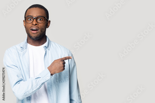 Surprised African American man with open mouth pointing to aside