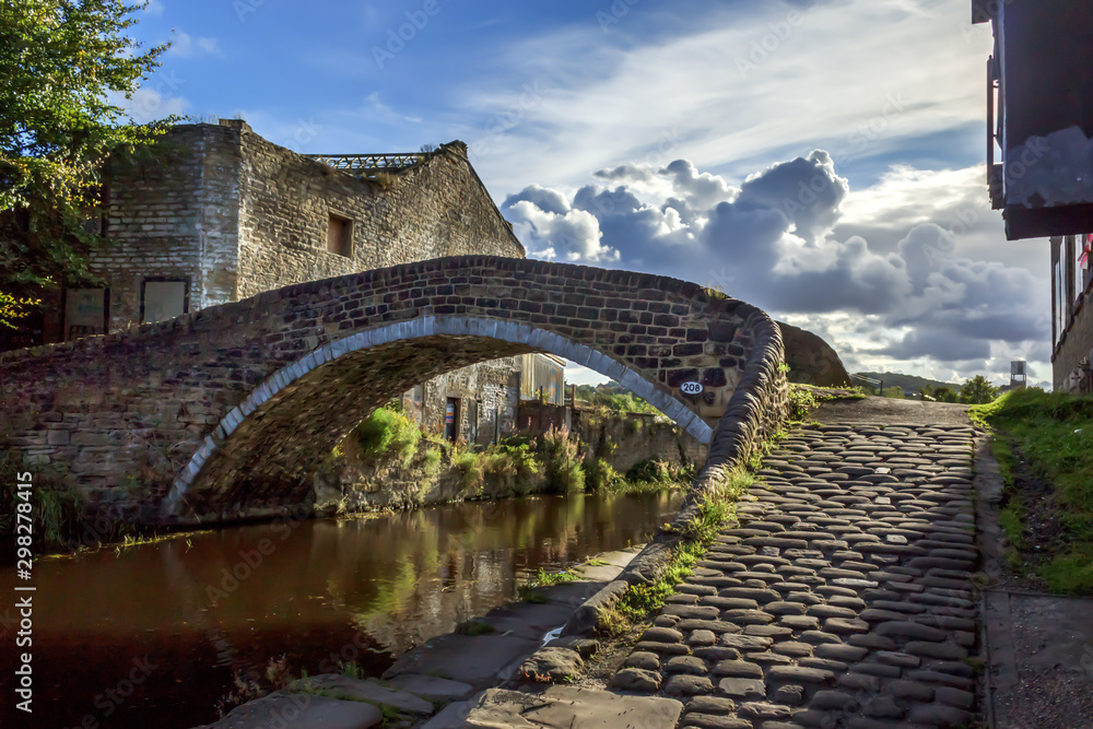 Obraz premium Bridge 208 at Dockfield in Shipley is pictured in vivid evening light and is one of the many packhorse style bridges so beloved of walkers and boaters along the Leeds and Liverpool Canal