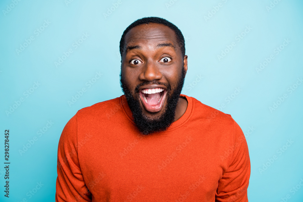 Closeup photo of attractive dark skin guy toothy beaming smiling open mouth unexpected good news positive mood wear orange jumper isolated blue color background Closeup photo of attractive dark skin guy toothy beaming smiling open mouth unexpected good news positive mood wear orange jumper isolated blue color background