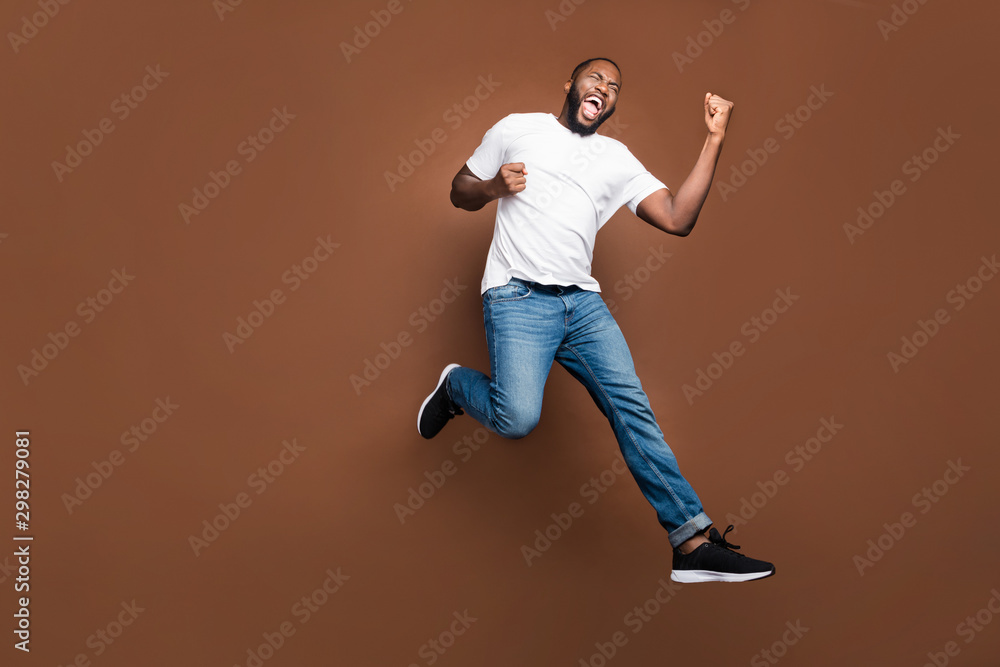 Full length body size photo of cheerful positive excited crazy ecstatic overjoyed man rejoicing about having bought new discounted jeans denim footwear white t-shirt jumping running isolated pastel